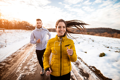 Active athletes sportive couple running with strong persistence on the road in winter nature in the morning.